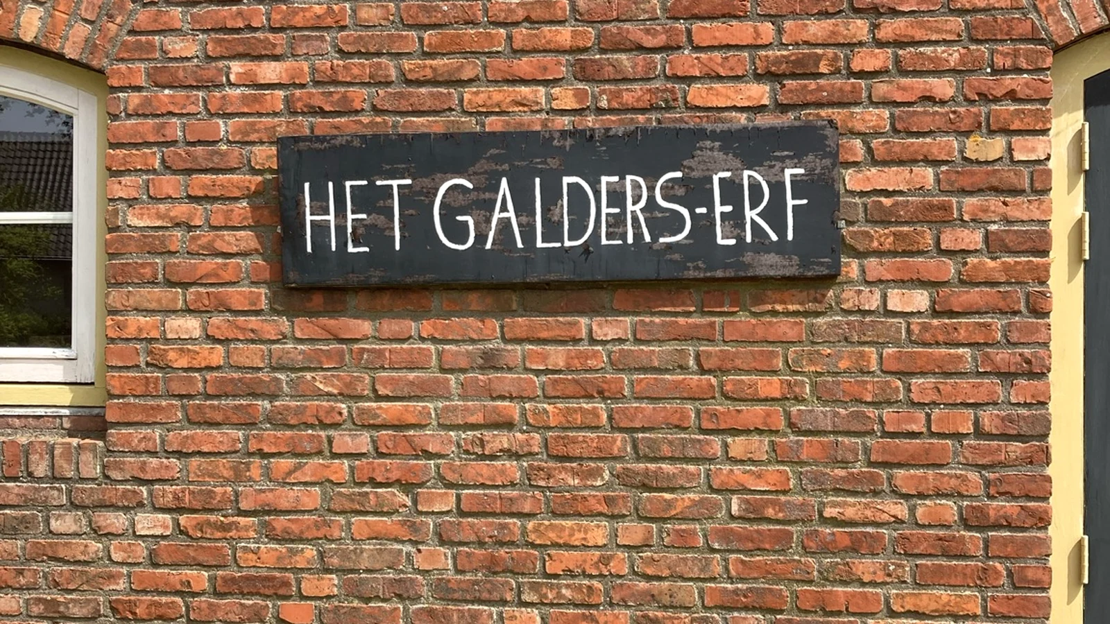 Het naambord van Het Galders Erf op de bakstenen gevel